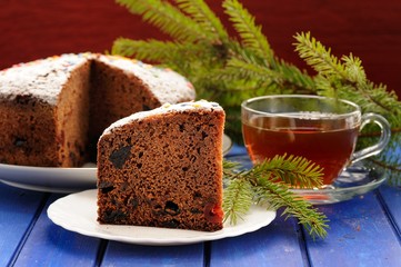 Chocolate fruit cake with black tea and green fur tree branch on