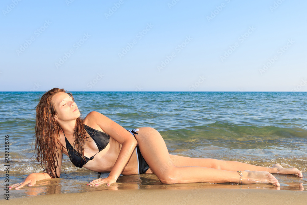 Wall mural pretty young woman in bikini on the beach