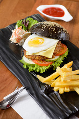 Modern black burger serve with french fries and coleslaw
