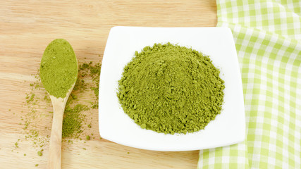 The Japanese matcha green tea powder on the spoon on wooden board and green cotton fabric.