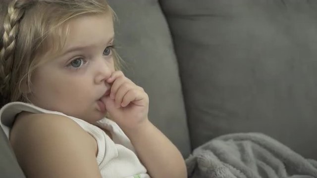 Views of a child engrossed in entertainment  She sucks her thumb.