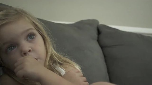 Views of a child engrossed in entertainment  She sucks her thumb.