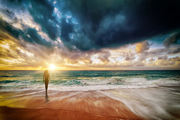 Beautiful silhouette of young woman in sea at sunset