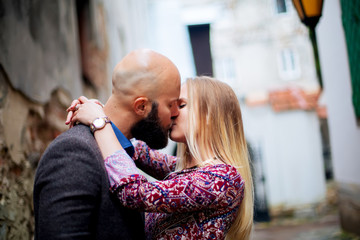 Happy couple low waist hugging and smiling, kissing on the background of old building