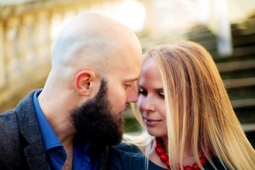 One beautiful stylish couple of young woman and senior man with long black beard sitting embracing close to each other outdoor in autumn street on stairs sunny day, horizontal picture