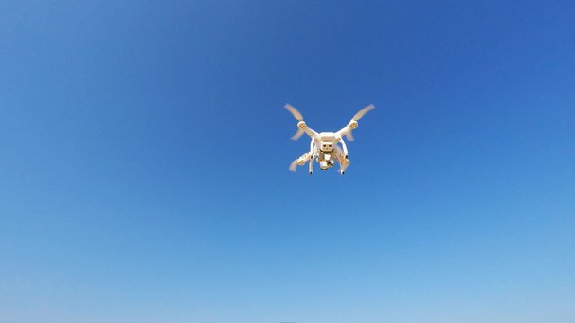 White remote controlled drone equipped with high resolution video camera hovering in mid air