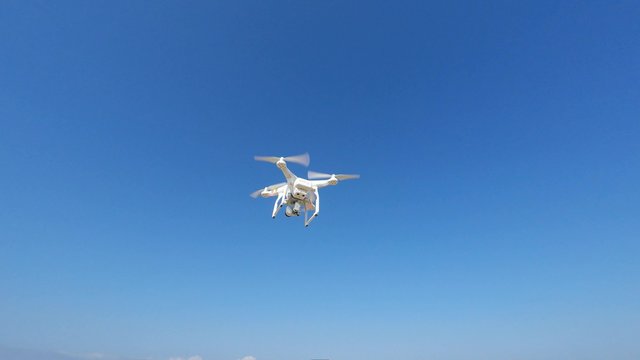 White remote controlled drone equipped with high resolution video camera hovering in mid air