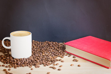 Coffee cup and coffee beans with book over wood