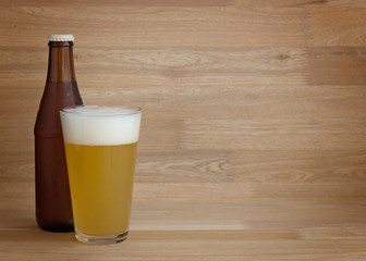 Wheat beer in glass and bottle over wood