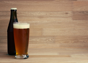 Red beer in glass and bottle over wood