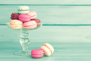 Colorful macaroons in a glass vase over turquoise wood