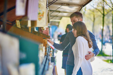 Romantic couple in Paris selecting a book from a bookseller