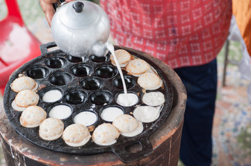 A man is cooking Kanom Krok , kind of Thai sweetmeat