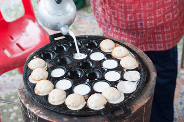 A man is cooking Kanom Krok , kind of Thai sweetmeat