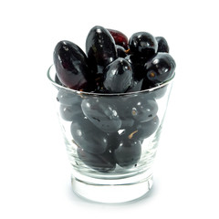 Black grapes in a glass isolated on a white background.