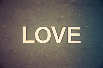 Word LOVE created of wood letters over vintage chalkboard, retro filter applied, conceptual image