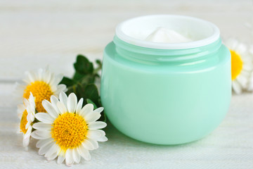 Fototapeta na wymiar outdoor facial cream with chrysanthemum on wooden background