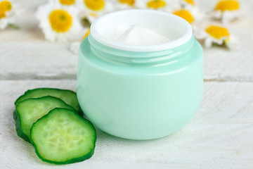 Obraz na płótnie Canvas outdoor facial cream with chrysanthemum and cucumber on wooden background