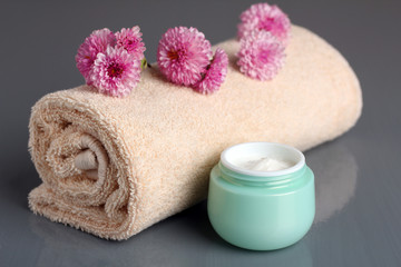 Obraz na płótnie Canvas outdoor facial cream with chrysanthemum and towel on wooden background