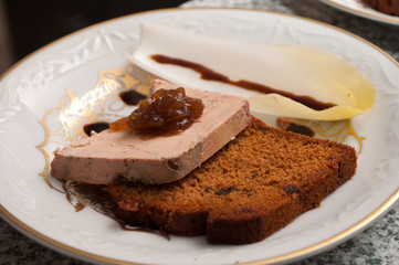 Fototapeta na wymiar assiette de foie gras accompagné de pain d'épices et feuille d'endive et confit d'oignon