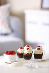Beautiful chocolate cupcakes with cream and raspberry on table
