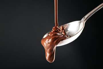 Chocolate poured on a spoon on dark background