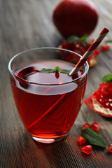 A glass of tasty juice and garnet fruit, on wooden background