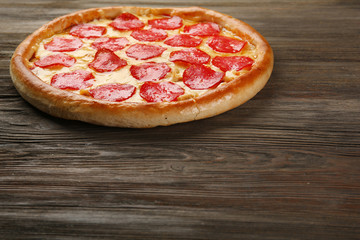 Tasty pizza with salami on wooden background