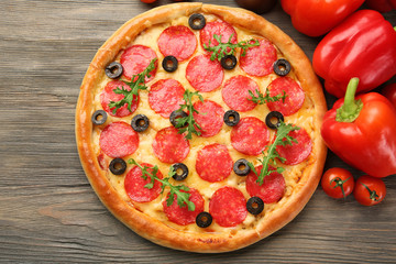 Tasty pizza with salami and red vegetables on wooden background, close up