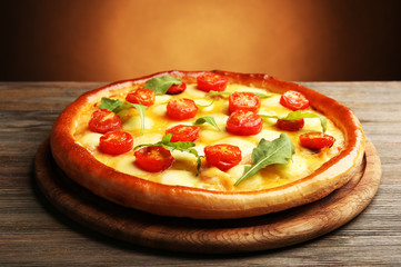 Pizza Margherita with arugula on brown background