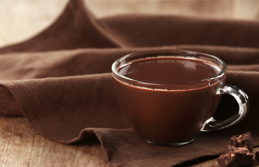 Cup of cacao with chocolate and napkin on wooden table