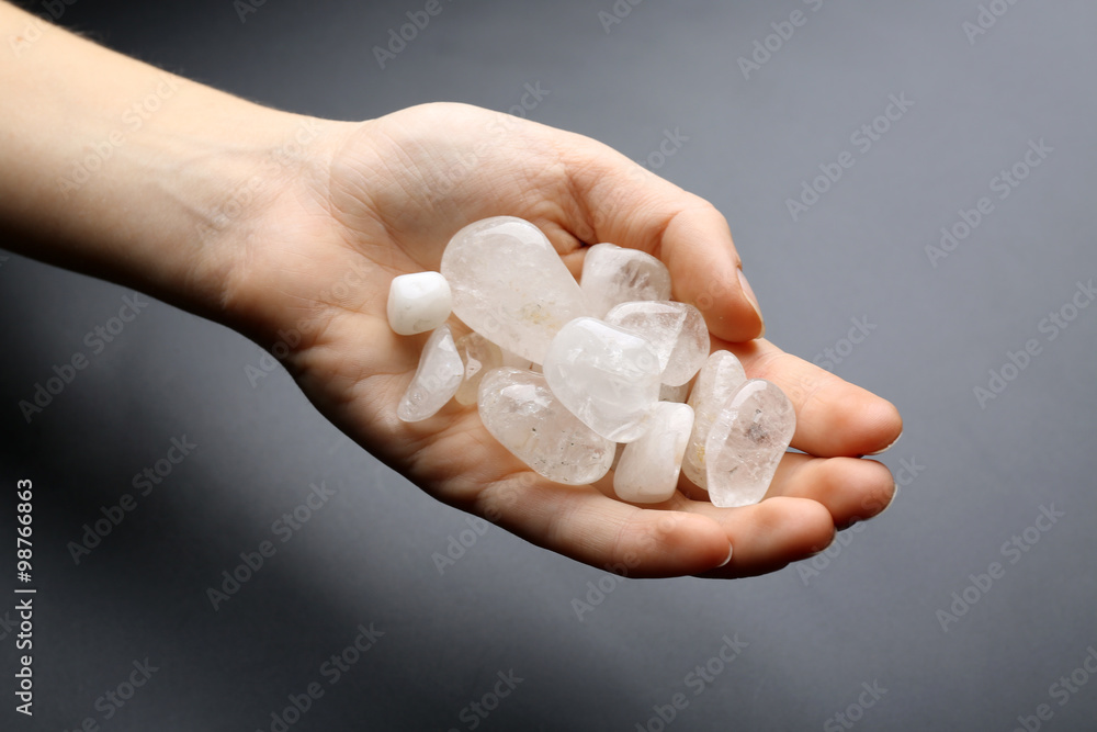 Canvas Prints Woman holding semiprecious stones in her hand on dark grey background