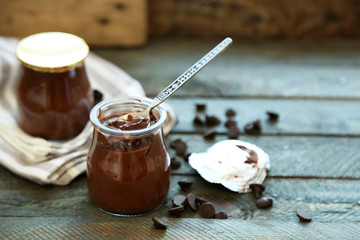 Chocolate dessert in a small glass jars on wooden background