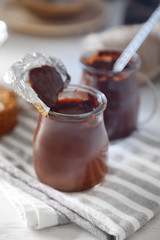 Chocolate dessert in a small glass jars on wooden background