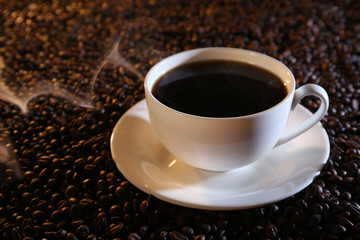 Cup of hot coffee on coffee beans background