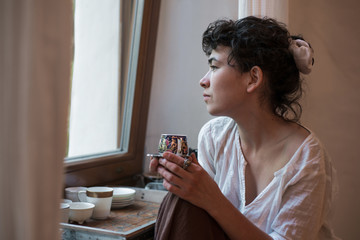Asian woman looking out the window and drinking tea