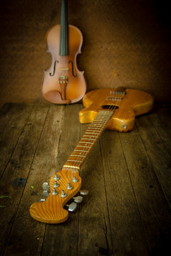 Acoustic guitar and violin resting against an old steel background