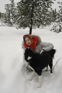 Девочка играет с собакой в снегу
