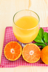Glass of orange juice with orange slice on soft wooden background