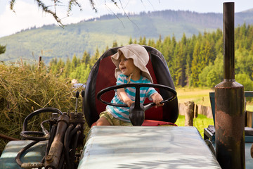 Portrait of little blond boy in tractor in summer © Peter Kosut