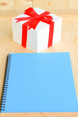 Gift box with red wrapped and blank paper put on wooden table