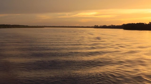Wonderful panoramic colored sunset on the large river Amazon with ripples. Amazonas State, Brazil