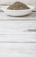 Black pepper powder in white bowl over wooden background