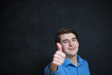 Fototapeta premium Happy young man is smiling and showing thumbs up. Dark backgroun