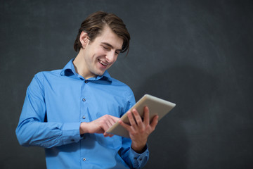 Smiling young male student with tablet pc against chalkboard