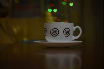 cup of coffee on the background bokeh in the form of hearts. Background to the Valentine's day