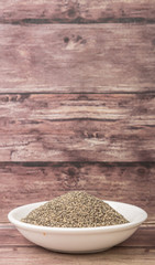 Black pepper powder in white bowl over wooden background