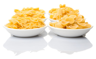 Dried pasta variety in shapes in white bowl over white background