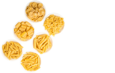 Dried pasta variety in shapes in white bowl over white background