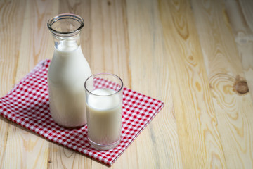 Milk bottle and milk glass put on wooden table.